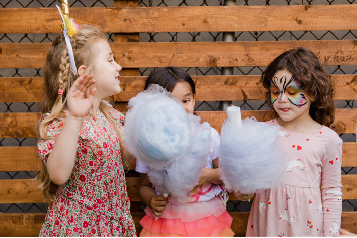 Three girls enjoying large fresh-spun cotton candy cones at a party
