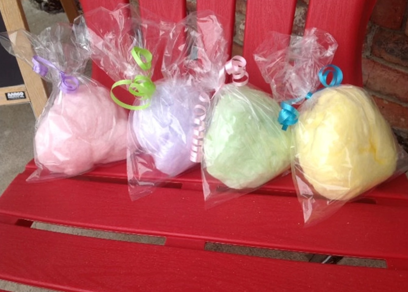 Individually bagged cotton candy party favors in pink, purple, green, and yellow, tied with colorful curling ribbons