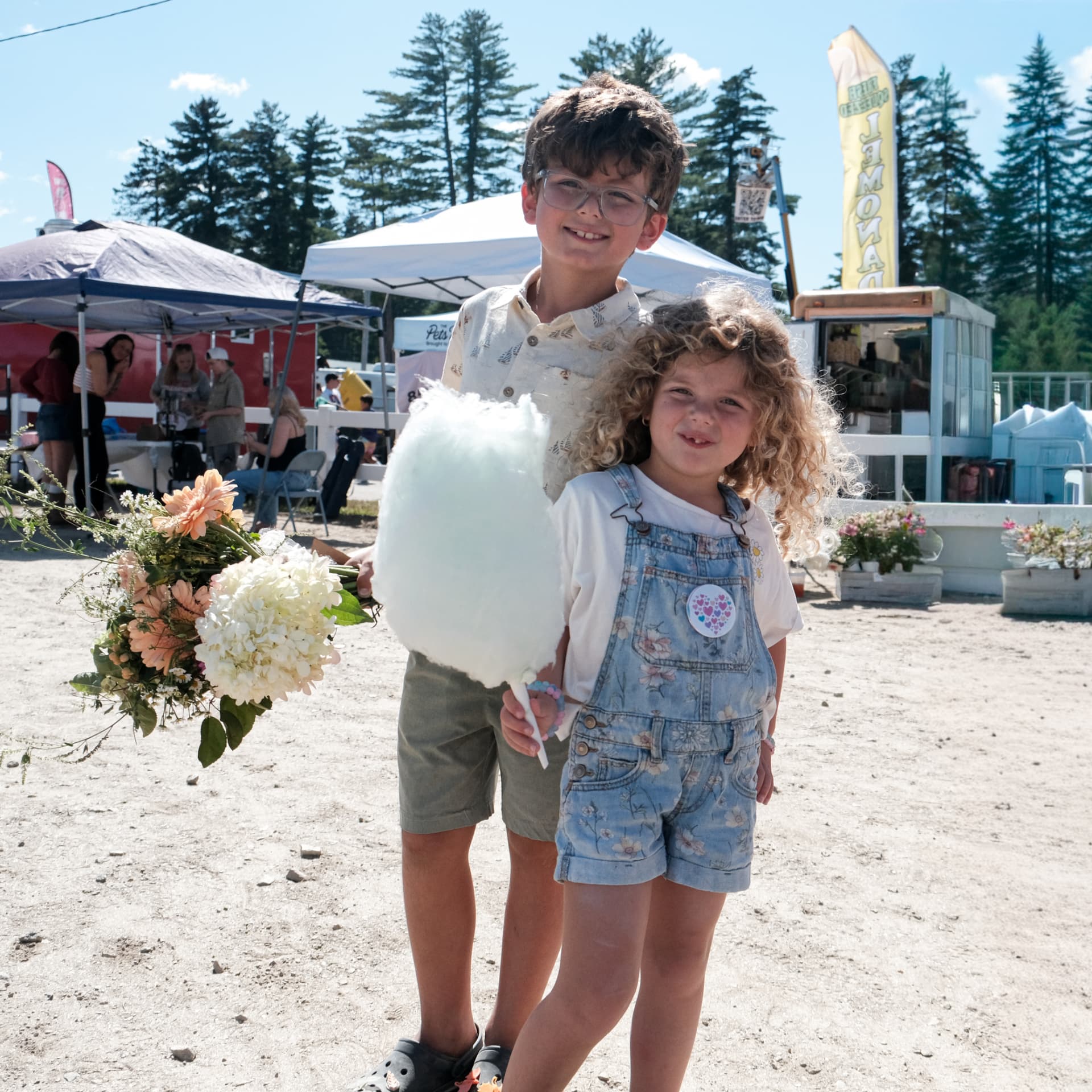 Two smiling children enjoying a large blue cotton candy