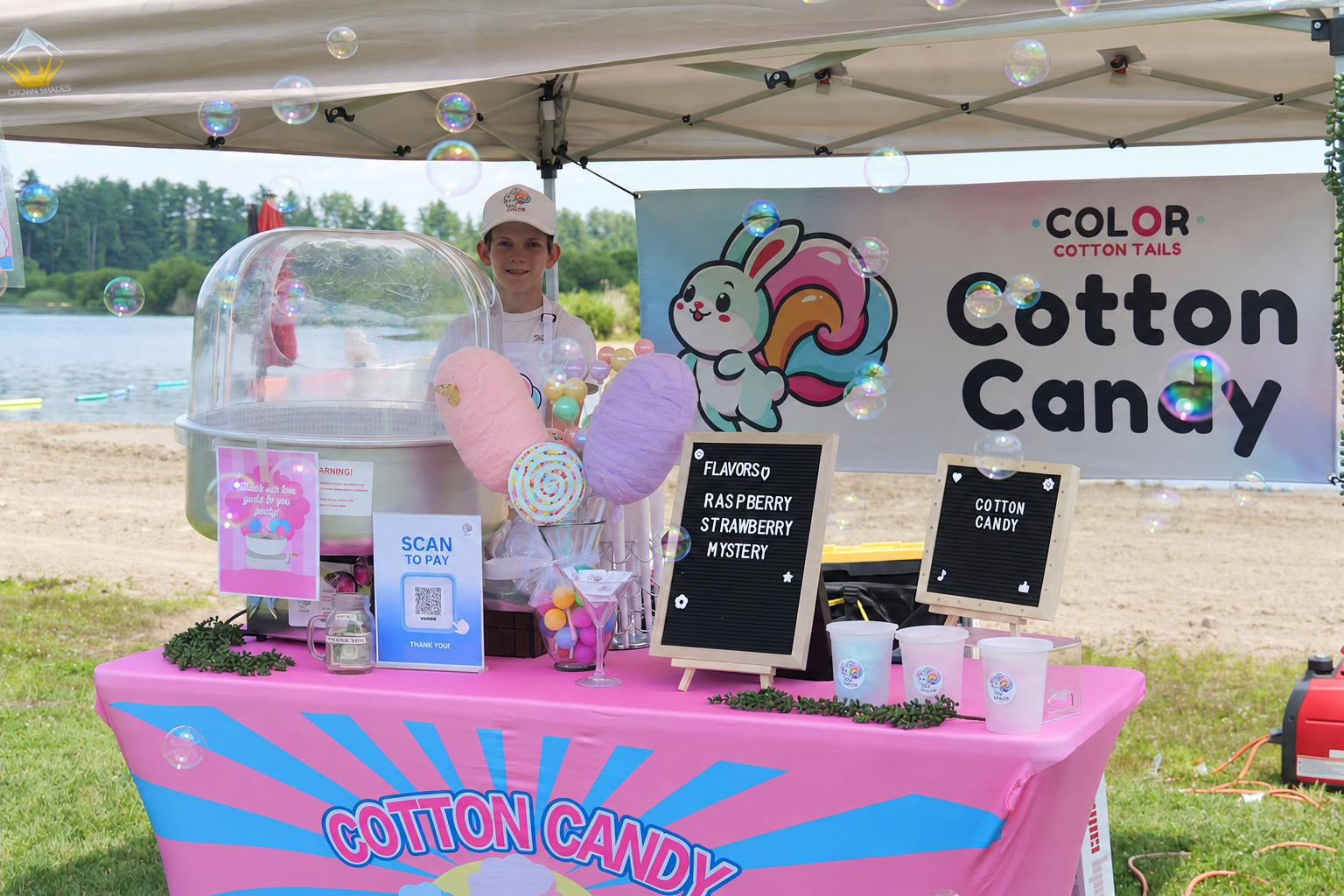 Liam standing at a lakeside Color Cotton Tails booth with bubbles floating around the cotton candy setup