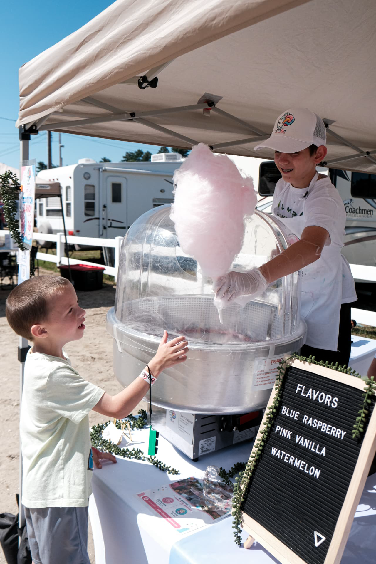 Liam handing a freshly spun pink cotton candy to a young guest